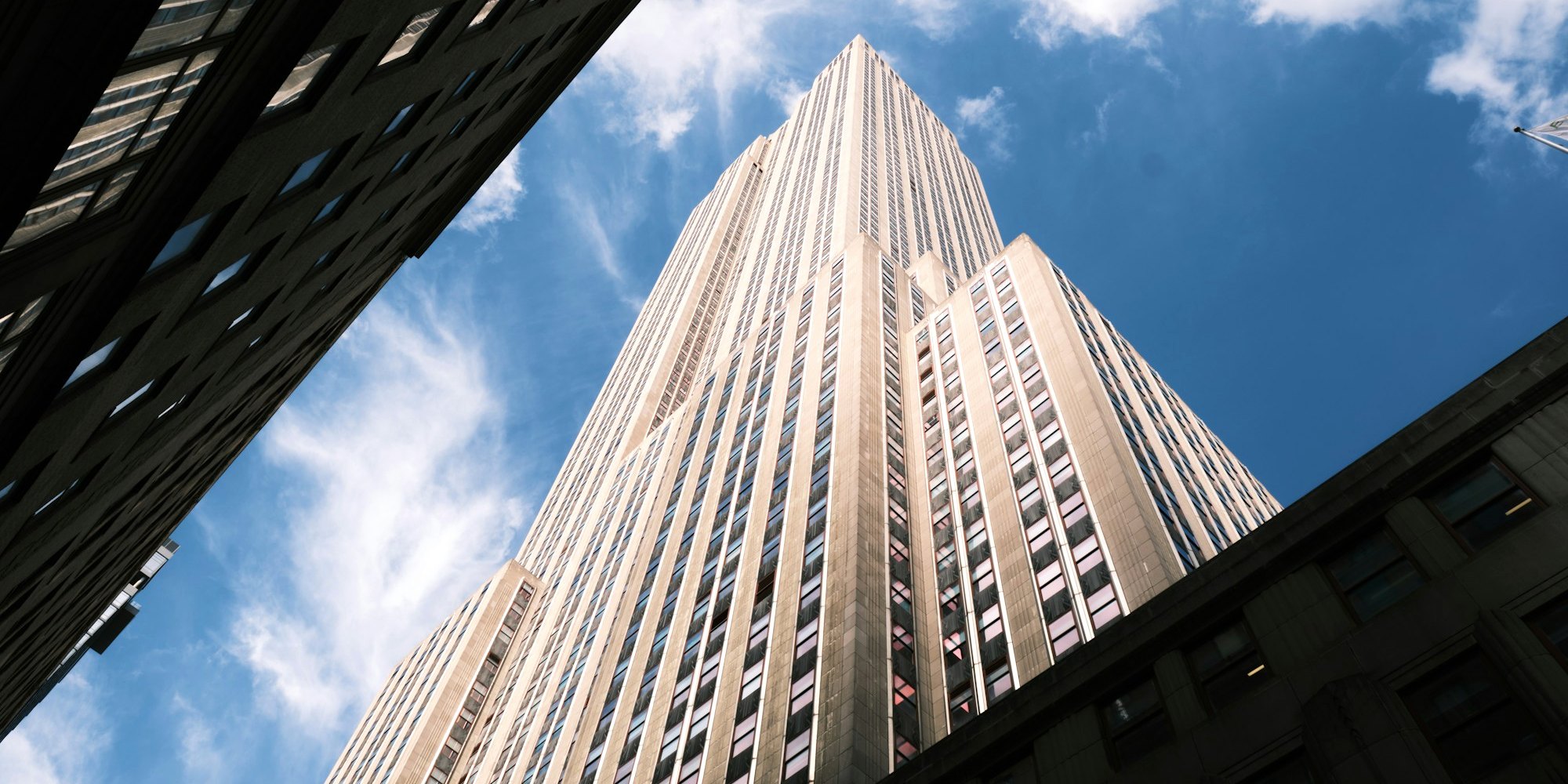 Looking up at the Empire State Building against a blue sky